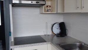 Una cocina con armarios blancos, un lavamanos de acero inoxidable y un reloj en la pared.