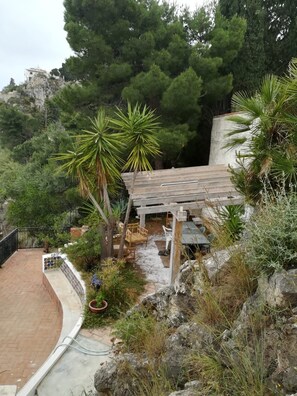 Un espace patio agrémenté d’une pergola, de sièges d’extérieur et offrant une vue sur une colline rocheuse.