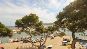 A marina with boats, cars, and vans parked. Trees line the area. - Front line apartment (Cala Rajada)