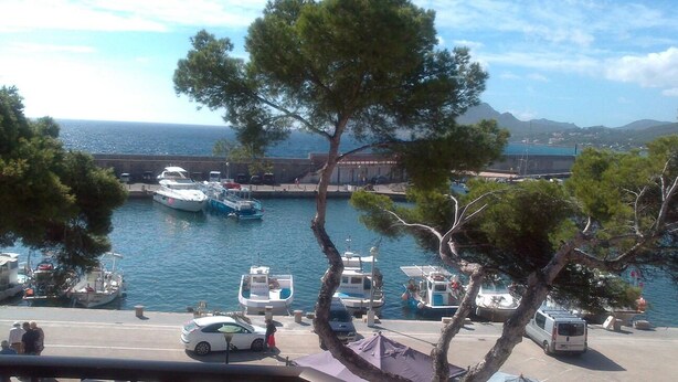 A marina with boats docked, a bridge in the background, and a coastal landscape. - Front line apartment (Cala Rajada)