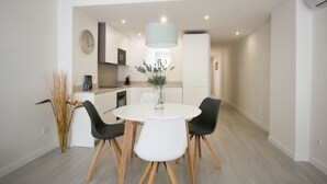 A modern dining area with a round table, four chairs, and a vase with flowers. - Front line apartment (Cala Rajada)