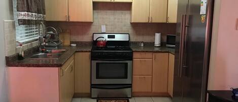 Een koelkast, een oven, kookgerei, borden en bestek