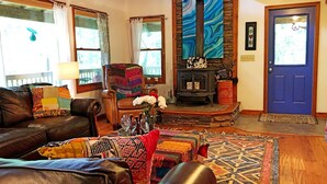 A cozy living room with leather sofas, a colorful rug, a fireplace, and a blue door. - Yoga & Peaceful, Elegant, Bohemian Vibes Surrounded by Forest (Blairsville)
