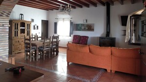 Un salon avec un plafond en bois, un canapé, une table à manger avec des chaises et une cheminée.