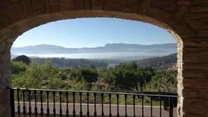 Une arche en pierre encadrant une vue sur un vignoble, des montagnes lointaines et un horizon brumeux.