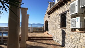 Un bâtiment en pierre doté d’un balcon, de climatiseurs et offrant une vue sur les montagnes.