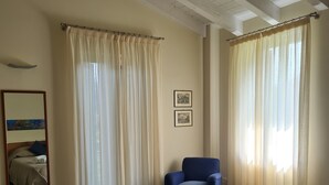 A hotel room with a bed, a chair, and two framed pictures on the wall. - LA COMMISSERIA Beautiful new house with private pool surrounded by nature (Salò)