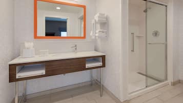 Une salle de bain moderne avec un meuble-lavabo blanc, une cabine de douche en verre et un miroir avec un cadre orange.
