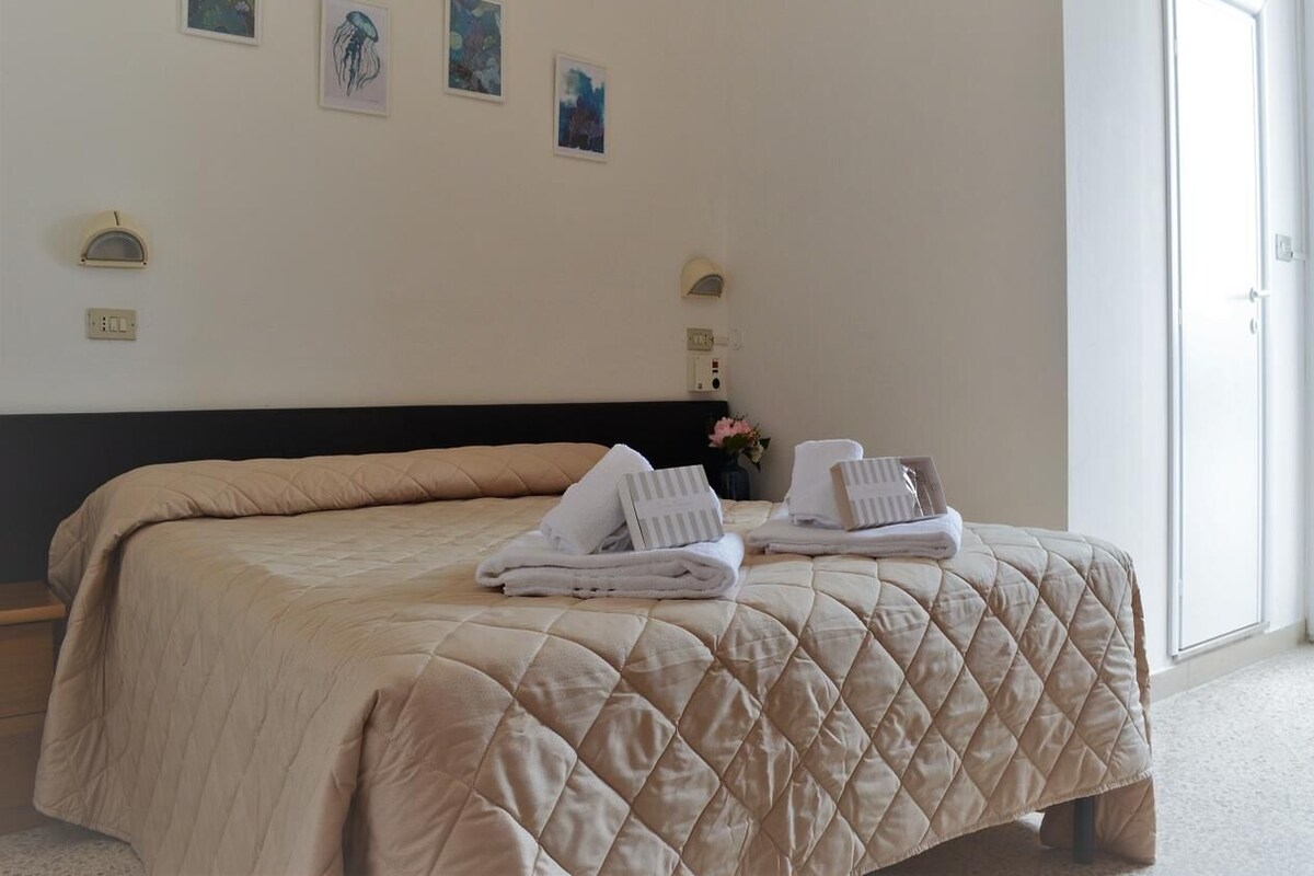 A hotel room with a large bed, two towels, and wall-mounted lights.