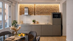 Une cuisine moderne avec un dosseret en pierre, un four encastré et un réfrigérateur.