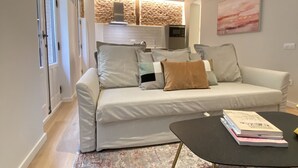 Un salon moderne avec un canapé, une table basse et une cuisine en arrière-plan.