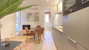 Eine moderne Küche mit einem großen Kühlschrank, einem Essbereich mit rundem Tisch und Stühlen sowie einer sichtbaren Klimaanlage.
