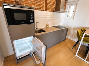 Una cocina moderna con refrigerador empotrado, horno de acero inoxidable y un lavamanos.