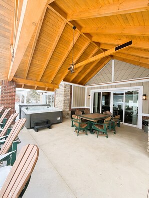 An outdoor patio with a hot tub, wooden chairs, and a dining table. - Lake House Villa by HHSW (Logan)