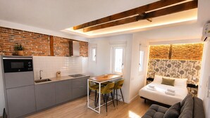 Une chambre d’hôtel compacte comprenant un coin cuisine, un canapé, un lit et un petit espace repas.