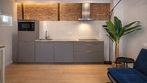 Une cuisine moderne avec un mur de briques derrière l’évier, un four à micro-ondes encastré et un évier.