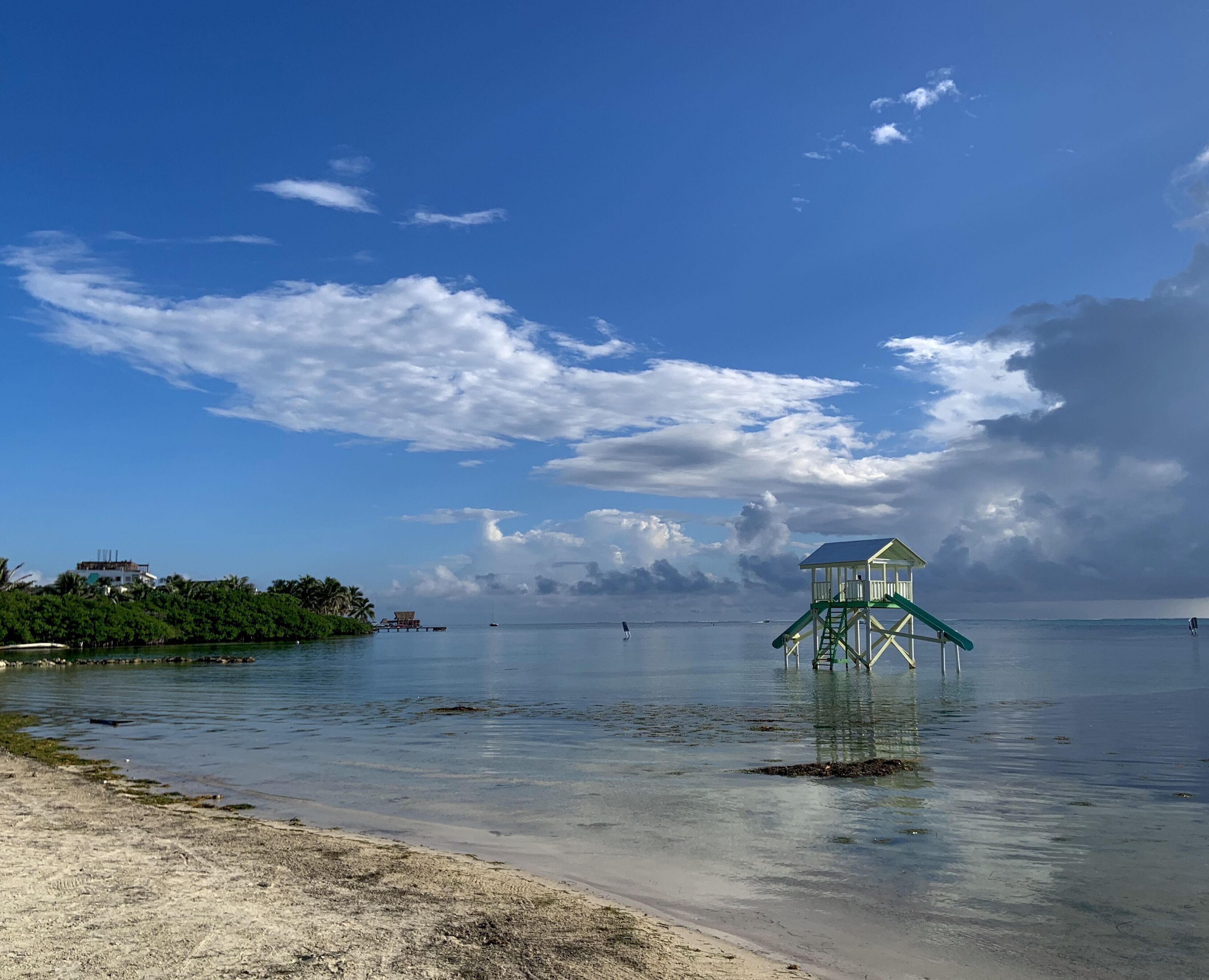 Una playa con una torre de salvavidas, agua tranquila y cielo despejado.