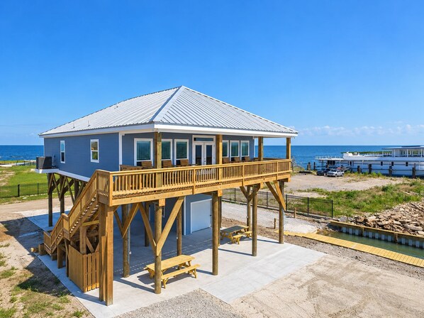 A beachfront house with a wooden deck and a covered porch.
