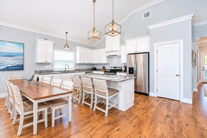 A spacious kitchen with white cabinetry, a central island, and a stainless steel refrigerator.