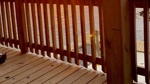 Un pontile in legno con ringhiera che si affaccia su un tramonto sull'acqua.