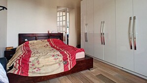 Een slaapkamer met een houten bed, een kledingkast en een raam.