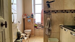 Een kleine badkamer met toilet, wastafel en een klein wasmandje.
