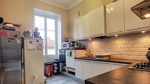 Een moderne keuken met witte kasten, een magnetron, een fornuis en een raam dat voor natuurlijk licht zorgt.