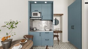 A compact kitchen with blue cabinets, a microwave, a sink, and a small dining area with a table and chairs.