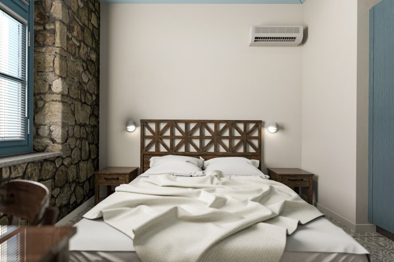 A bedroom with a stone wall, a wooden headboard, a bed with white linens, bedside tables, and an air conditioning unit.