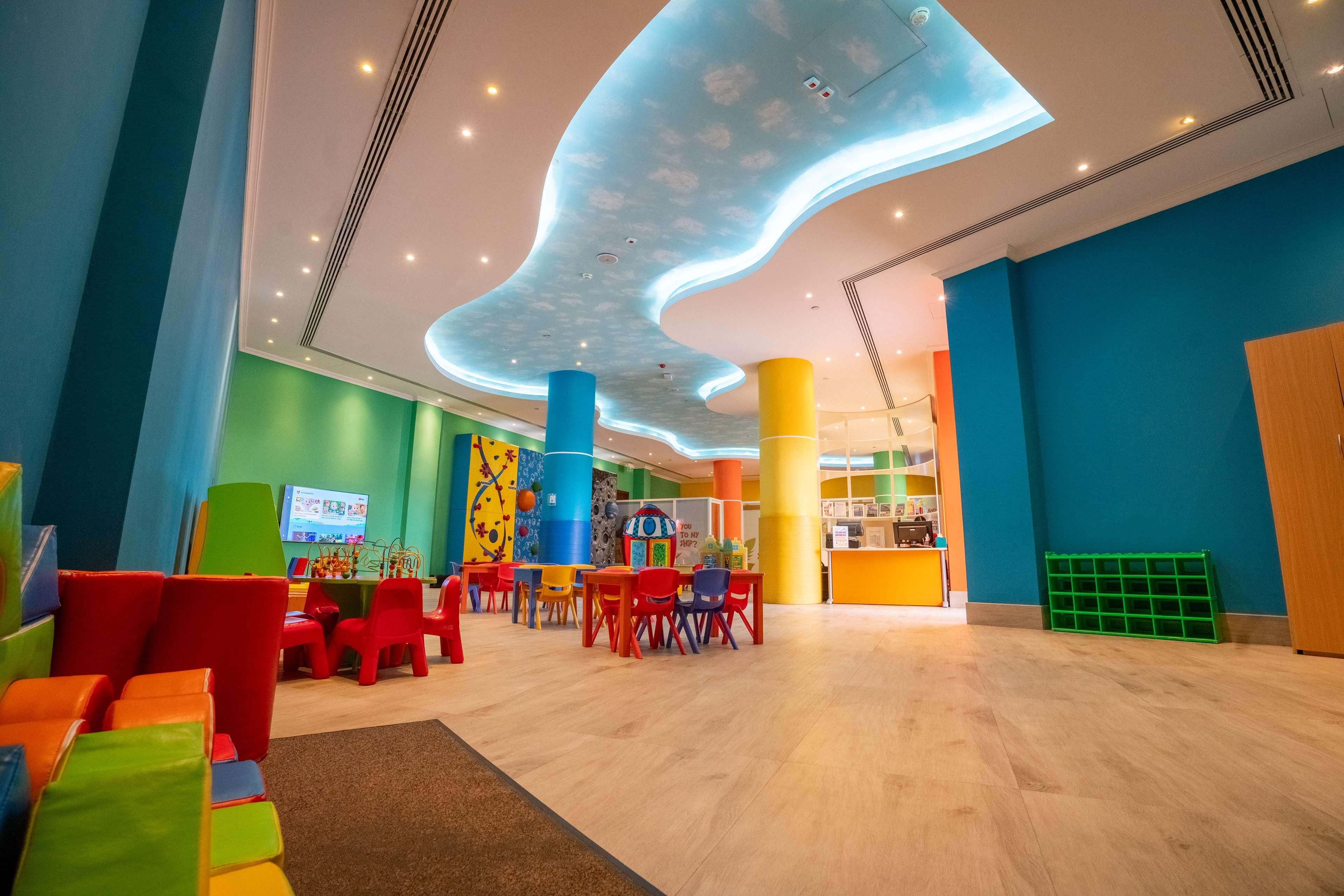 A brightly lit indoor space with colorful seating arrangements and a unique ceiling design.