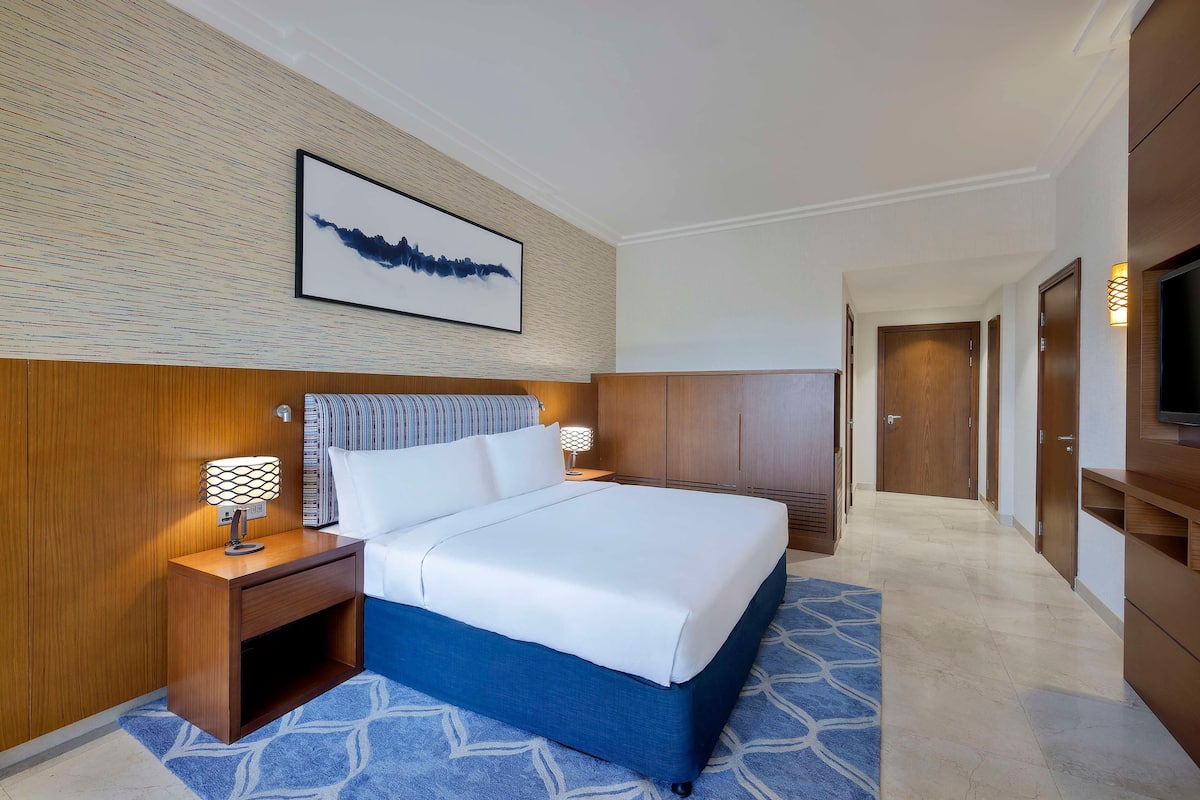 Een hotelkamer met een bed, nachtkastje, wanddecoratie en een televisie.