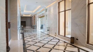 Un pasillo de hotel con piso de cuadros, puertas de vidrio y un diseño moderno.