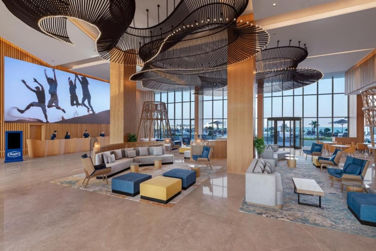 A spacious lobby with a large TV screen, modern furniture, and a view of the outdoors.
