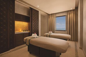 A hotel room with two beds, a large window with curtains, a decorative wall panel, and a small table with a candle. - Doubletree by Hilton Resort & Spa Marjan Island (Ras Al Khaimah)