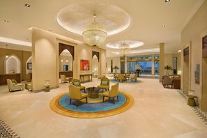 A spacious lobby with a central seating area, chandeliers, and a view of the cityscape. - Doubletree by Hilton Resort & Spa Marjan Island (Ras Al Khaimah)