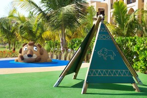 Ein Kinderspielbereich mit einer Rutsche, einer großen Tiermalerei und einer Zierpyramide.
