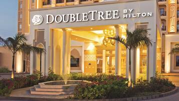 A hotel with a prominent 'DOUBLETREE BY HILTON' sign, multiple balconies, and a well-lit entrance.