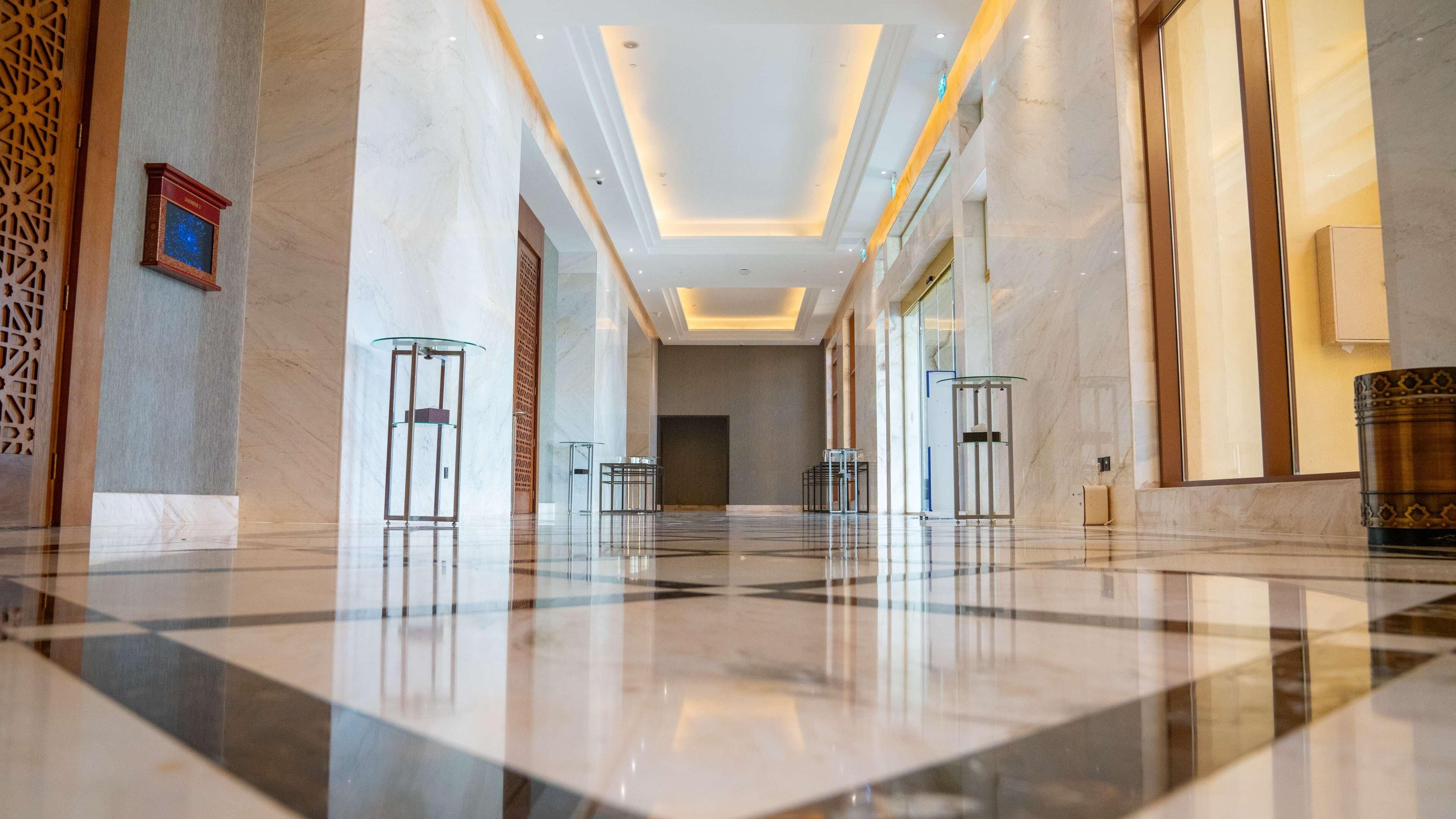A spacious lobby with marble floors, glass display cases, and a modern ceiling design.