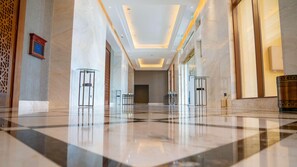 Un hall amplio con suelos de mármol, vitrinas de cristal y un diseño moderno en el techo.