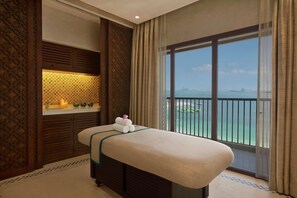 A massage table with towels, a view of the sea, and a patterned wall. - Doubletree by Hilton Resort & Spa Marjan Island (Ras Al Khaimah)