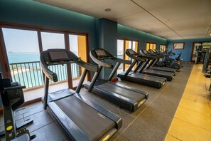 A gym with treadmills, exercise equipment, and large windows with a view of the sea. - Doubletree by Hilton Resort & Spa Marjan Island (Ras Al Khaimah)