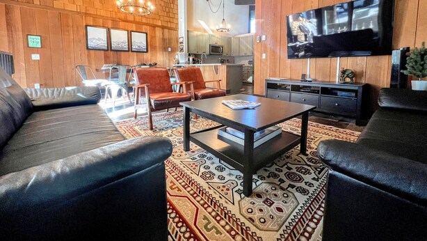 Un salon moderne avec un canapé, des fauteuils, une table basse et un téléviseur.