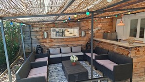 A covered outdoor seating area with wicker furniture, patterned rugs, and a central table. - Villa with pool near Lake Ste Croix (Régusse)