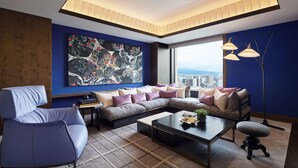 A modern living room with a sectional sofa, a blue armchair, a coffee table, and a large abstract painting on the wall.