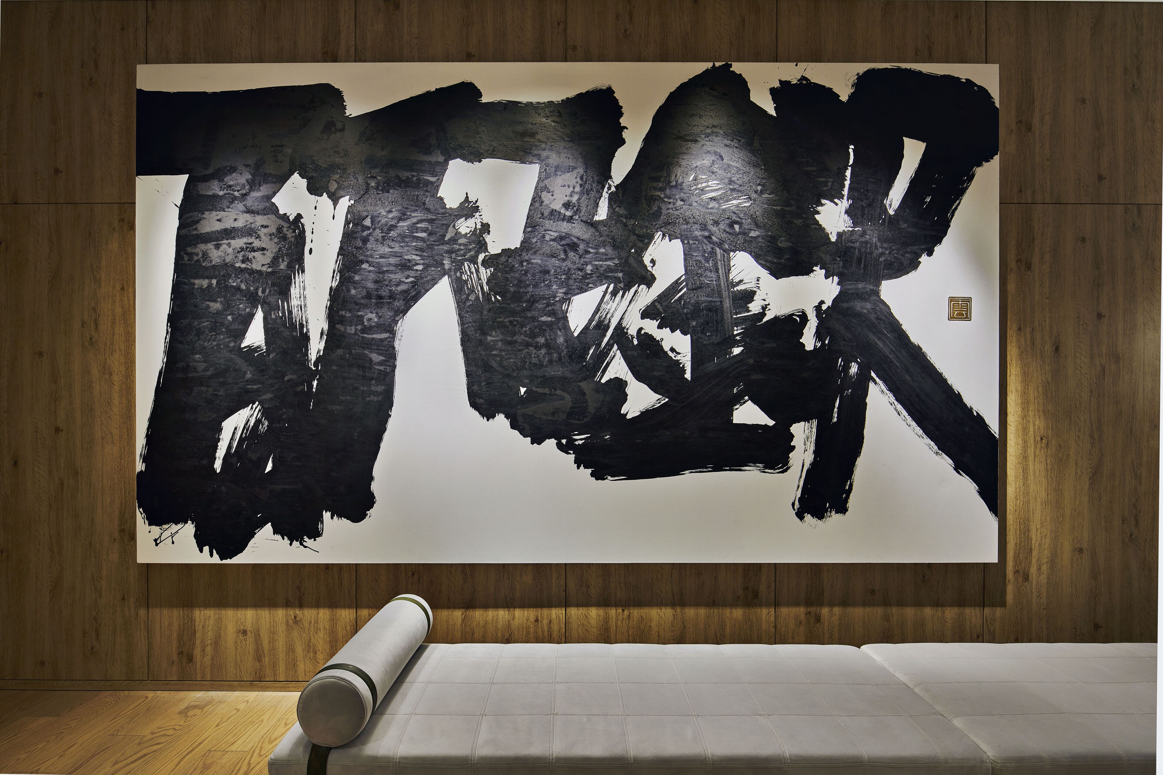 A large abstract painting on a wall in a room with wooden paneling and a white mattress on the floor.