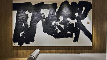 A large abstract painting on a wall in a room with wooden paneling and a white mattress on the floor.