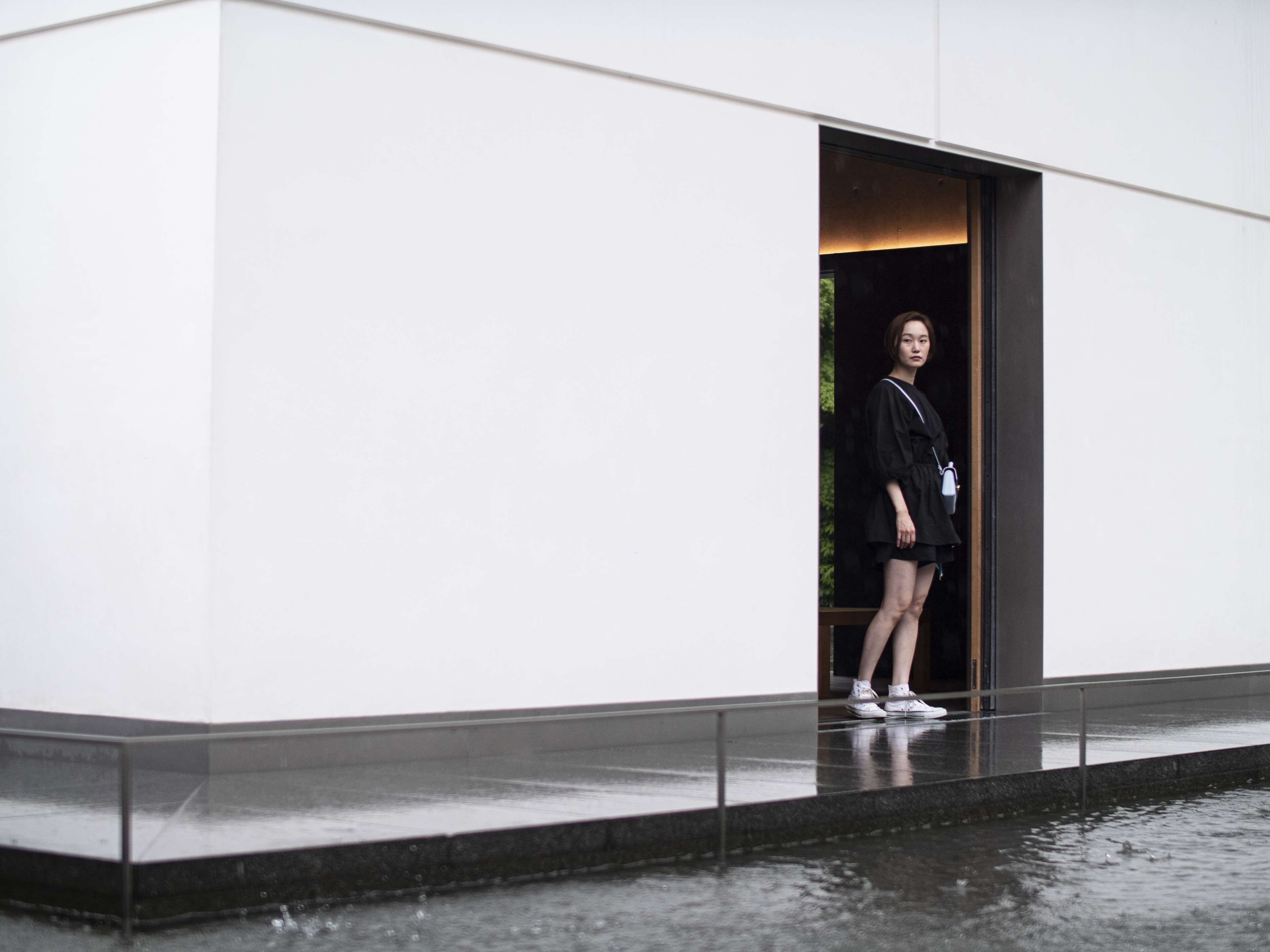 A person standing at the entrance of a building with a glass door.