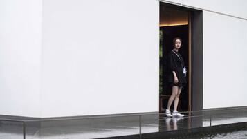 A person standing at the entrance of a building with a glass door.