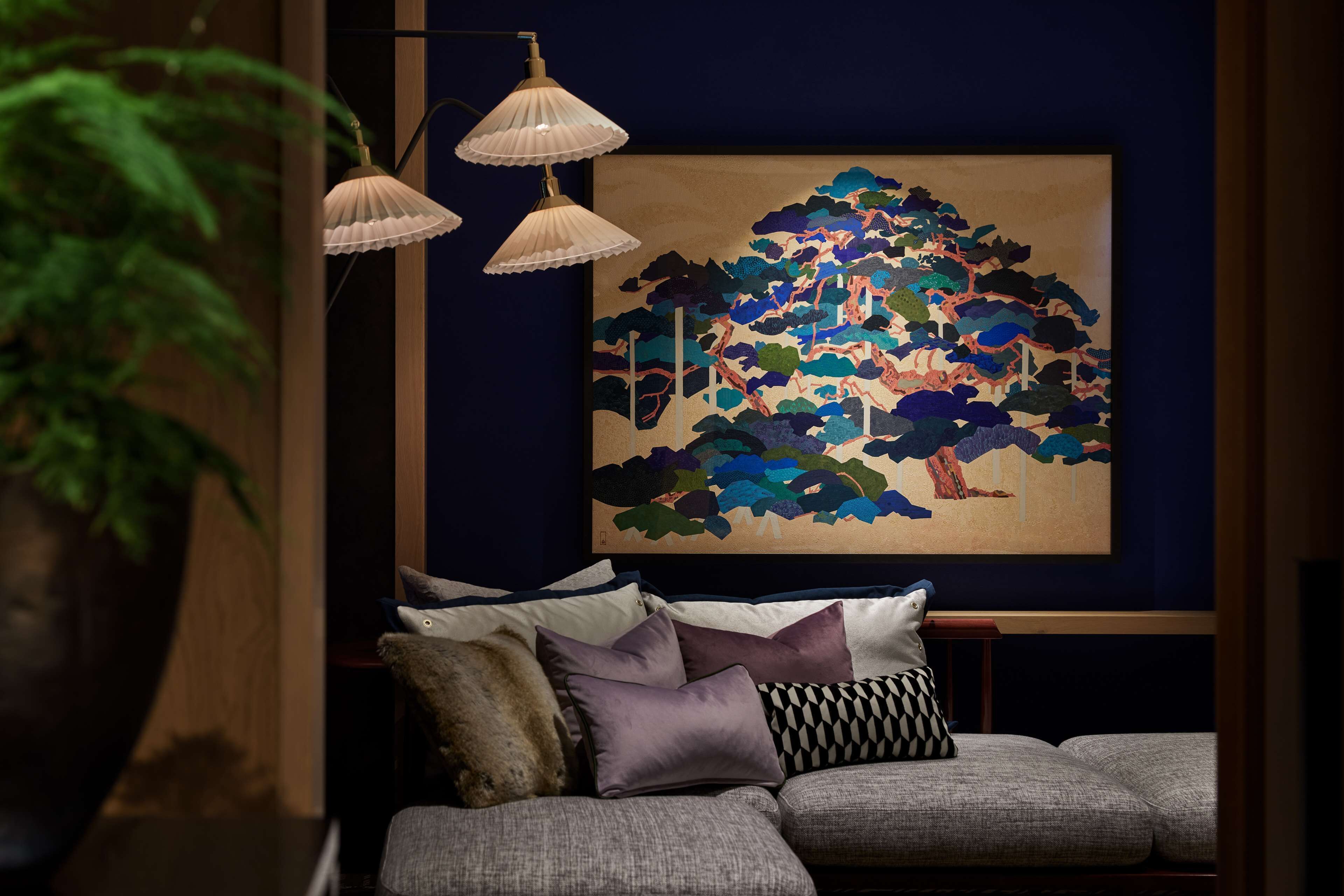 A modern living room with a sofa, decorative pillows, a large abstract painting, and a floor lamp.