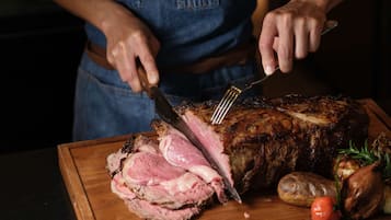 Una persona cortando un gran asado sobre una tabla de madera.